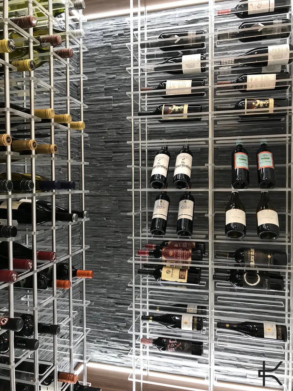 White steel racks against a stacked-stone wall, bottles displayed label-out.