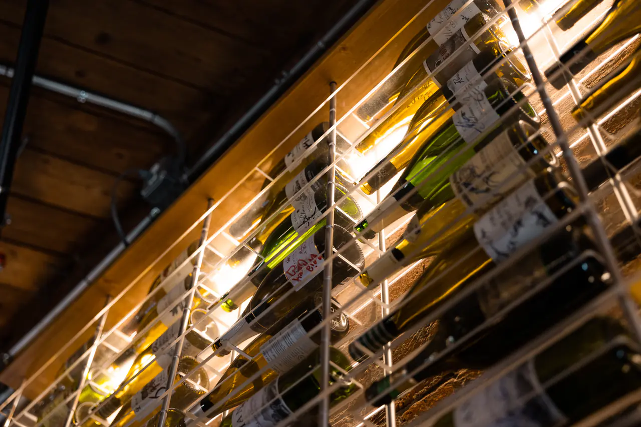 Wine bottles held in a white steel grid, seen from below at an angle.