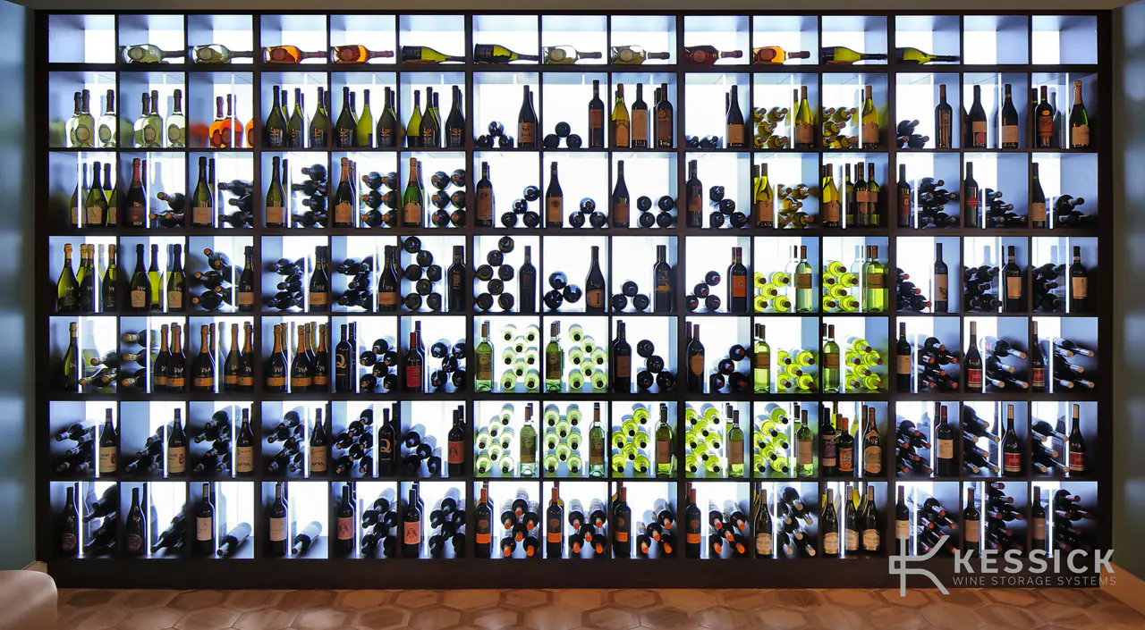 A backlit wall of cubbies holding wine.
