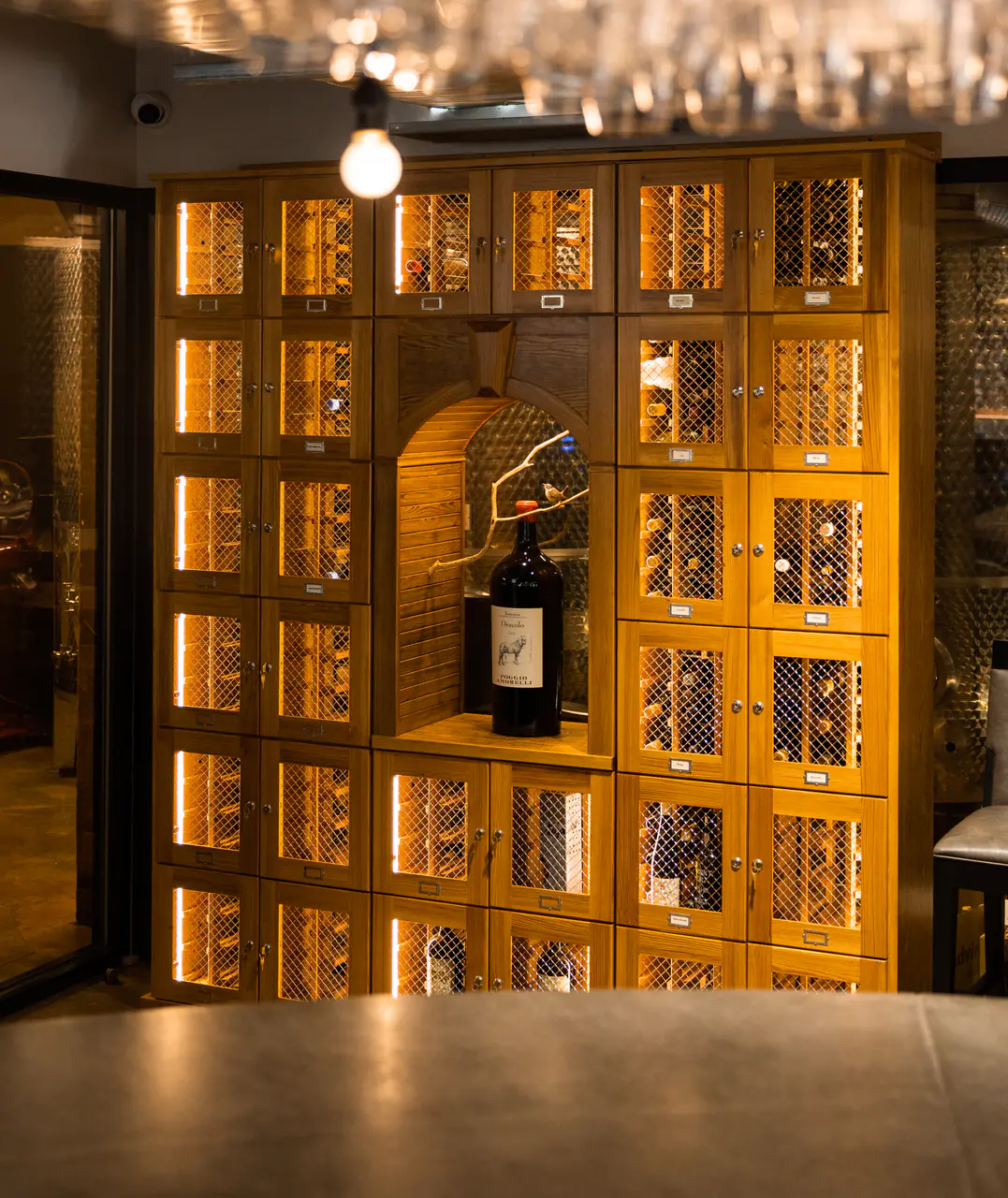 A wall of timber wine lockers with lattice doors around an arched niche.
