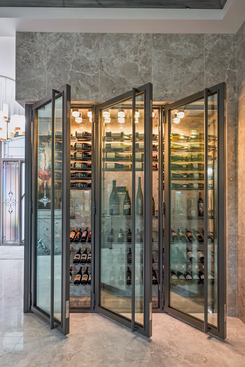 A steel-framed glass wine cabinet with its doors open, set into a marble wall.