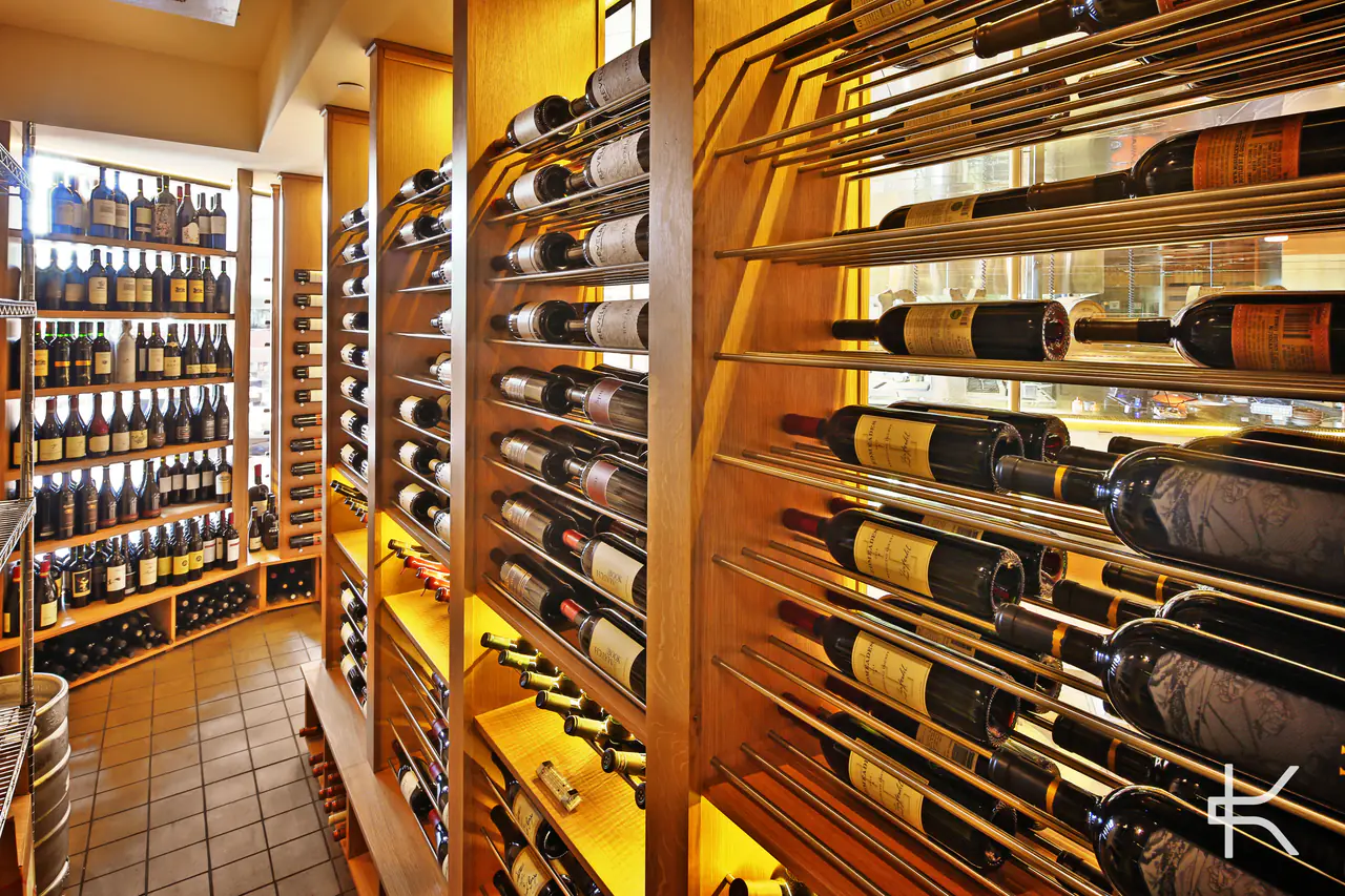 Bottles on steel rods, labels forward, against lit timber cabinetry.