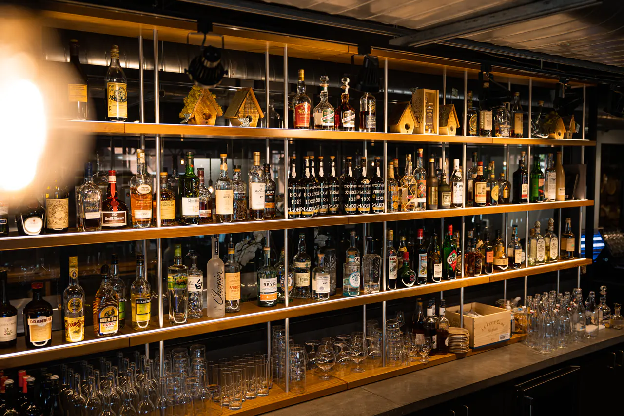 Timber shelves on white steel uprights holding spirits, glassware and small birdhouses.