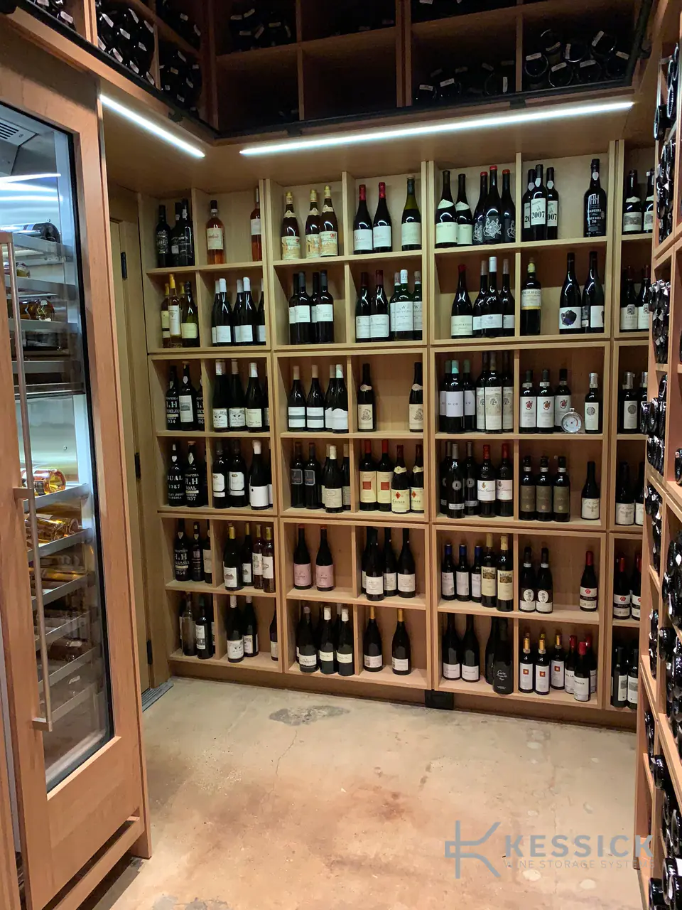 A small wine room of timber cubbies seen through an open glass door.