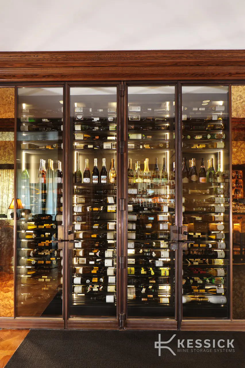 Glass doors framed in dark metal, wine racks lit behind them.