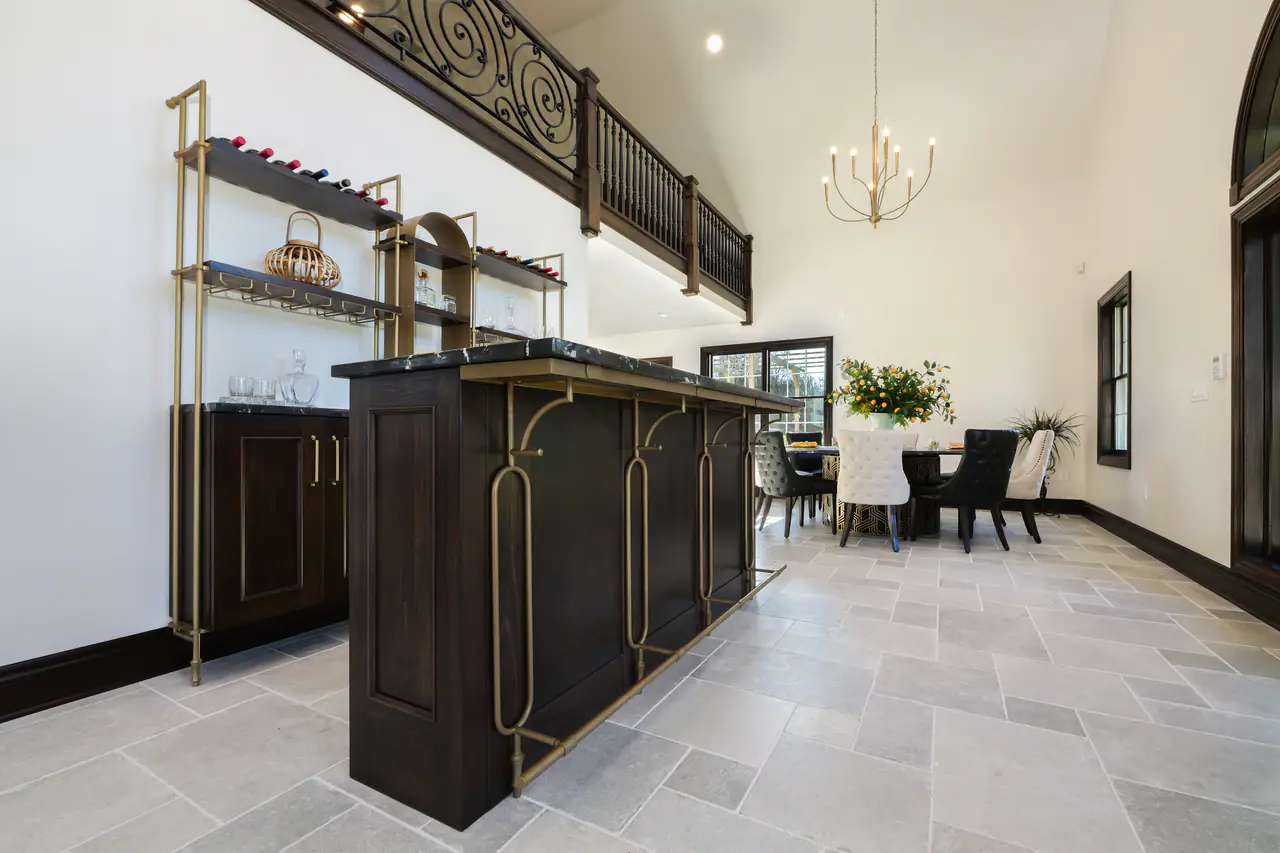 A dark timber bar on brass supports in an open-plan room, a dining table beyond.
