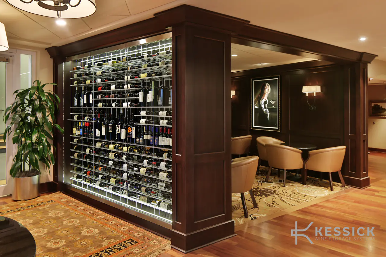 A glass wine wall seen from a lounge, armchairs beyond.
