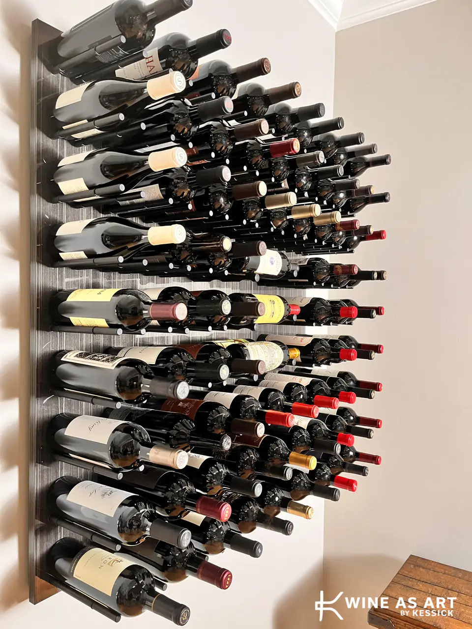 A panel of wine on slim pegs, bottles fanned out from the wall, seen at an angle.