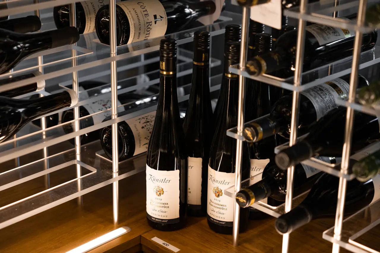 Bottles standing on a timber shelf among white steel racks.