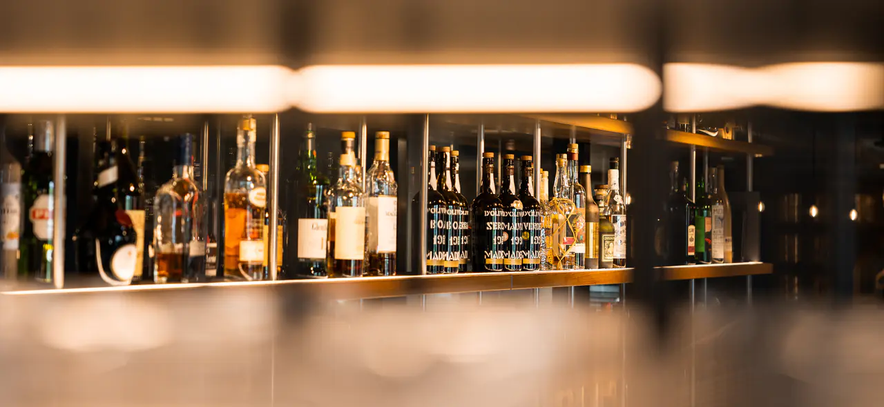 A single shelf of spirits beneath a strip of light.