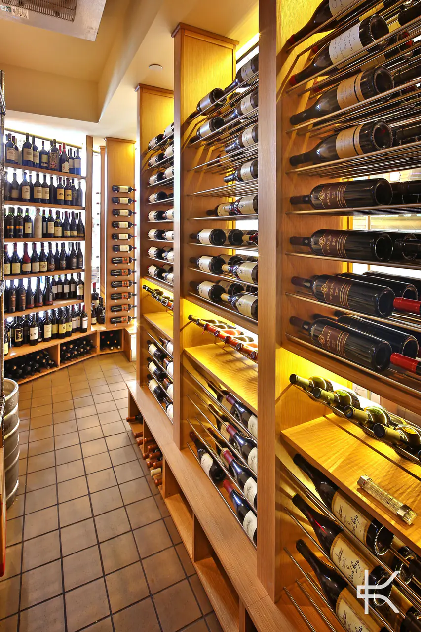 A narrow aisle between timber racks, bottles on steel rods.