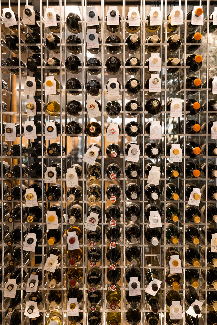 Bottles in a white steel grid, each with a hanging tag.