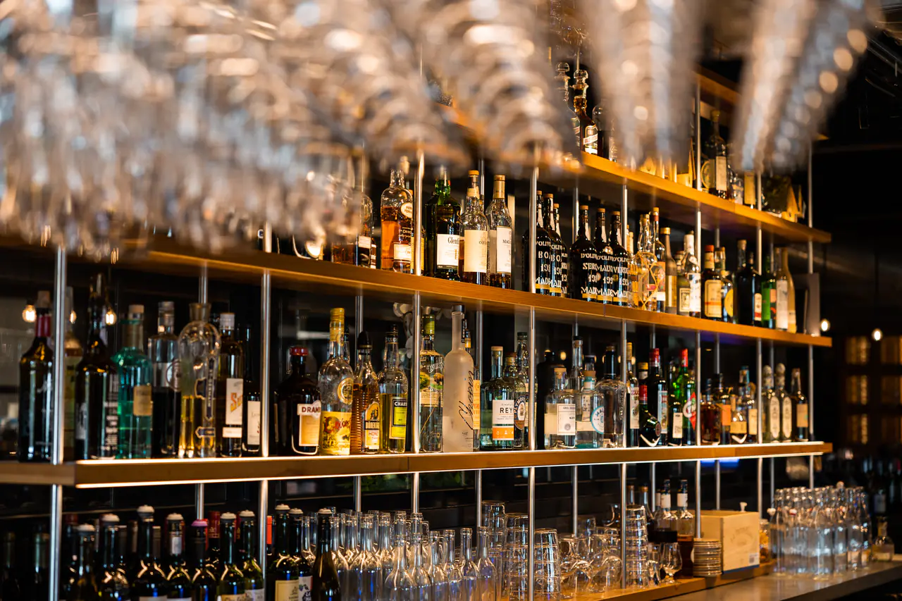 Stemware hanging above open shelves of spirits and glassware.