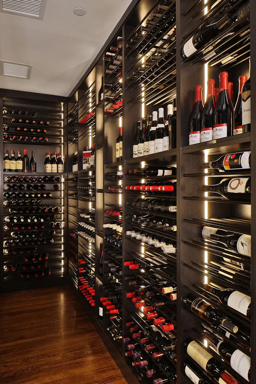 A narrow aisle between dark wine racks, lit in vertical lines.
