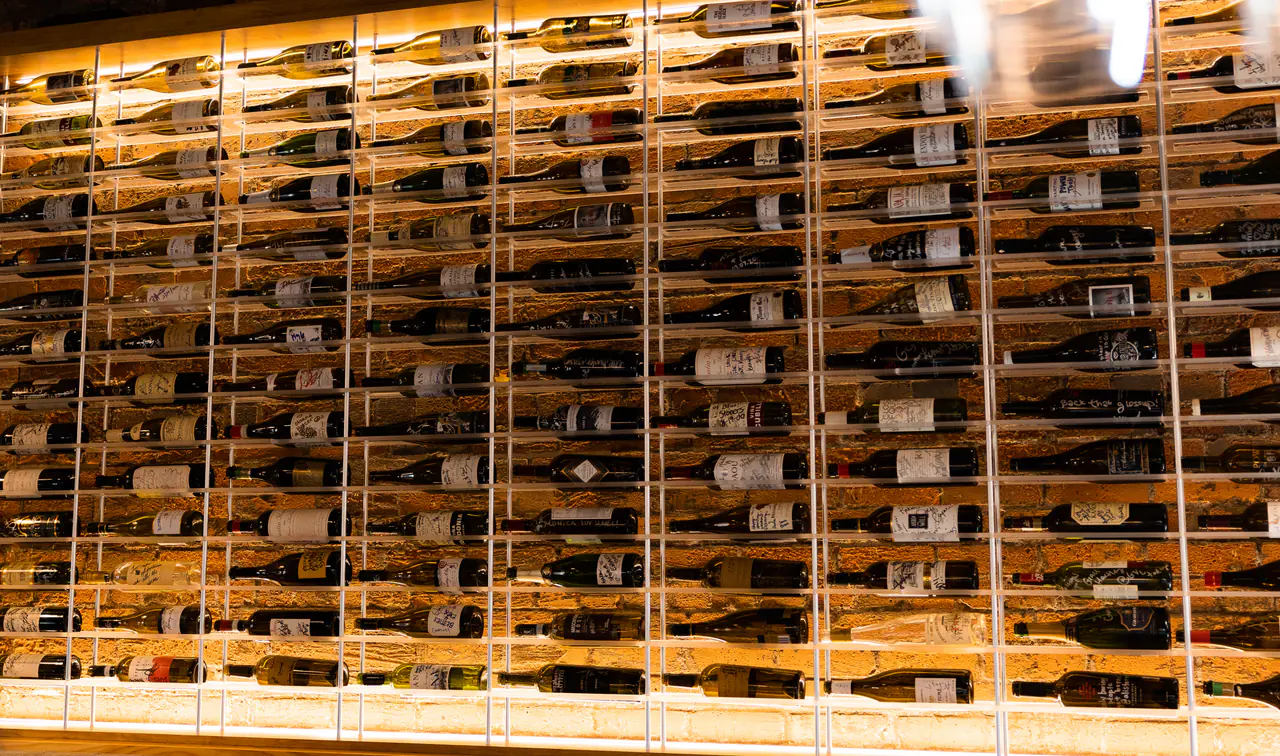A wall of wine in a white steel grid, lit from above and below.