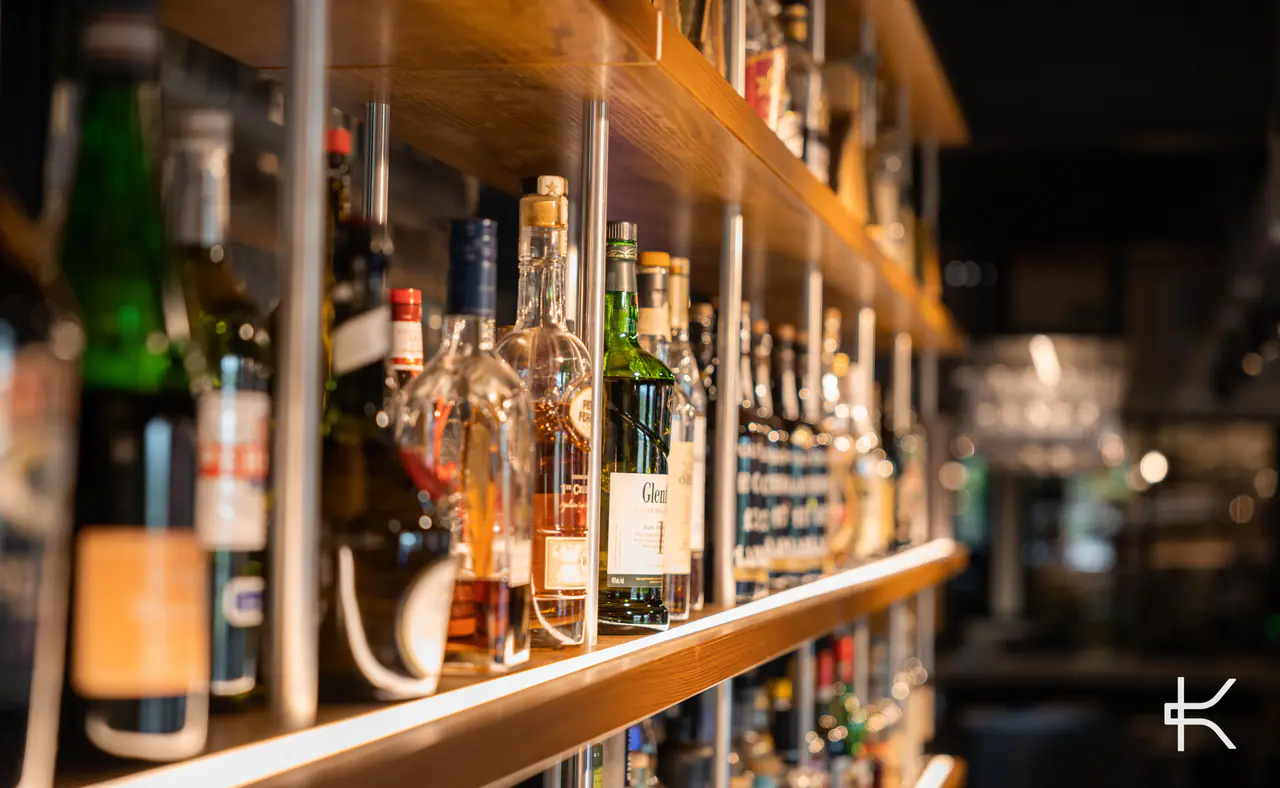 Spirit bottles on a timber shelf held by thin steel rods.