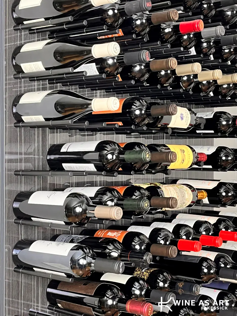 Bottles on pegs against a grey panel, seen from the side.