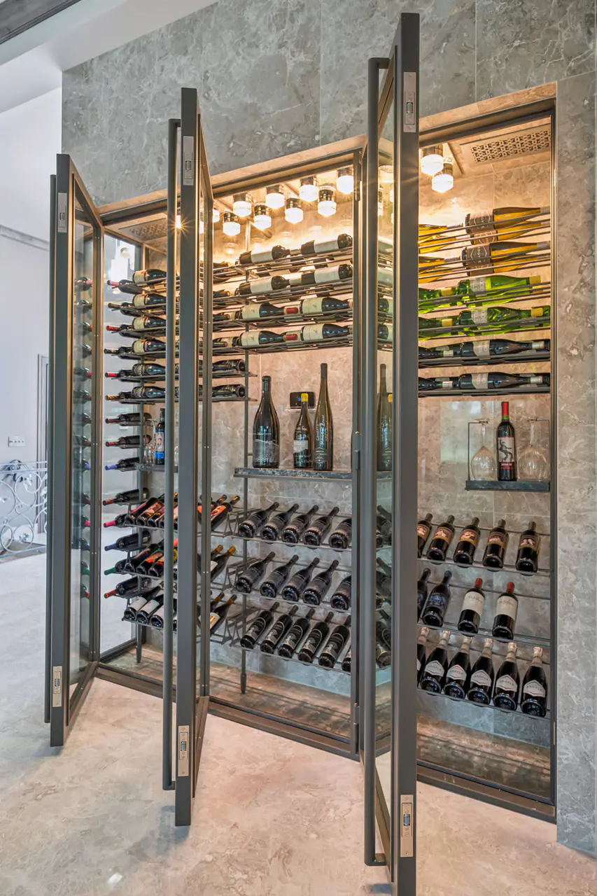 A glass wine cabinet standing open, bottles on steel rods inside.