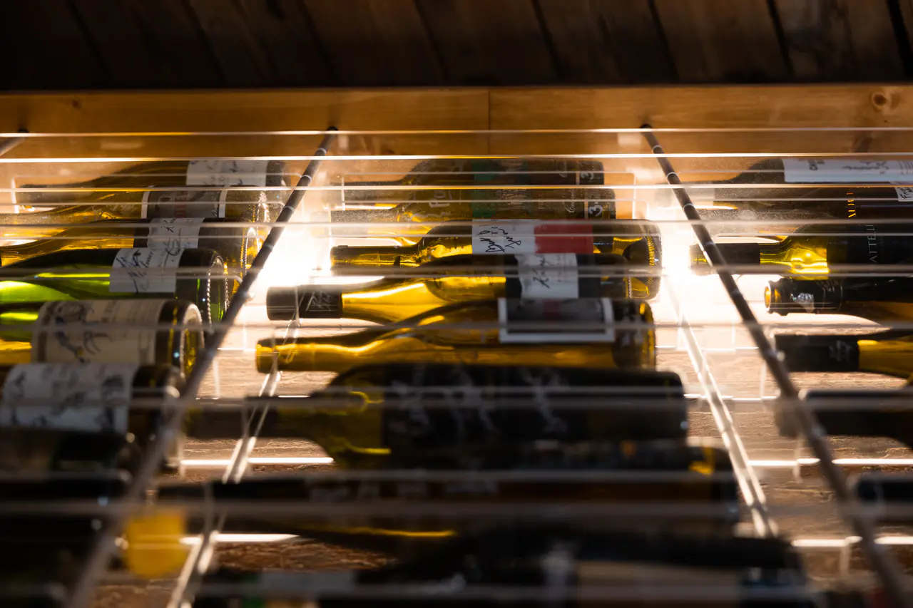Bottles lying in a white steel grid, seen from beneath, lit from behind.