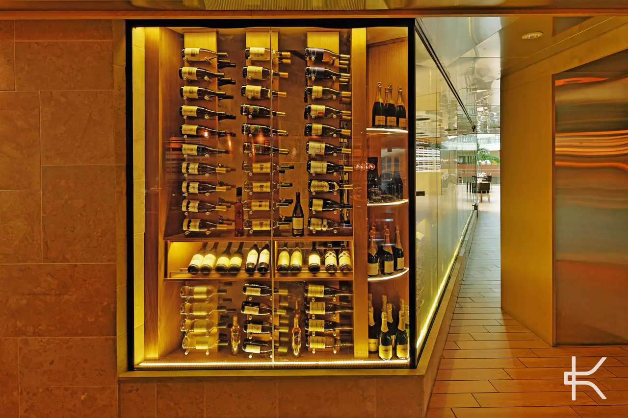 A lit wine niche set into a stone wall beside a glass corridor.