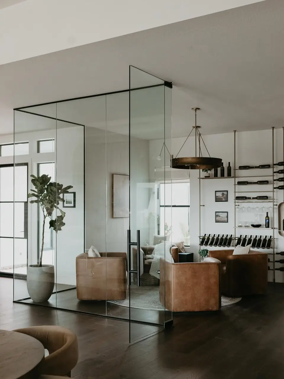 A glass-walled lounge seen from outside, slim metal wine shelves lining its far wall.
